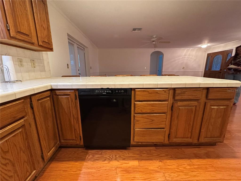 A kitchen island with a black dishwasher and oak cabinets sits on wood flooring — 10 FT CLINCH HEIGHTS ROAD, FROSTPROOF, FL