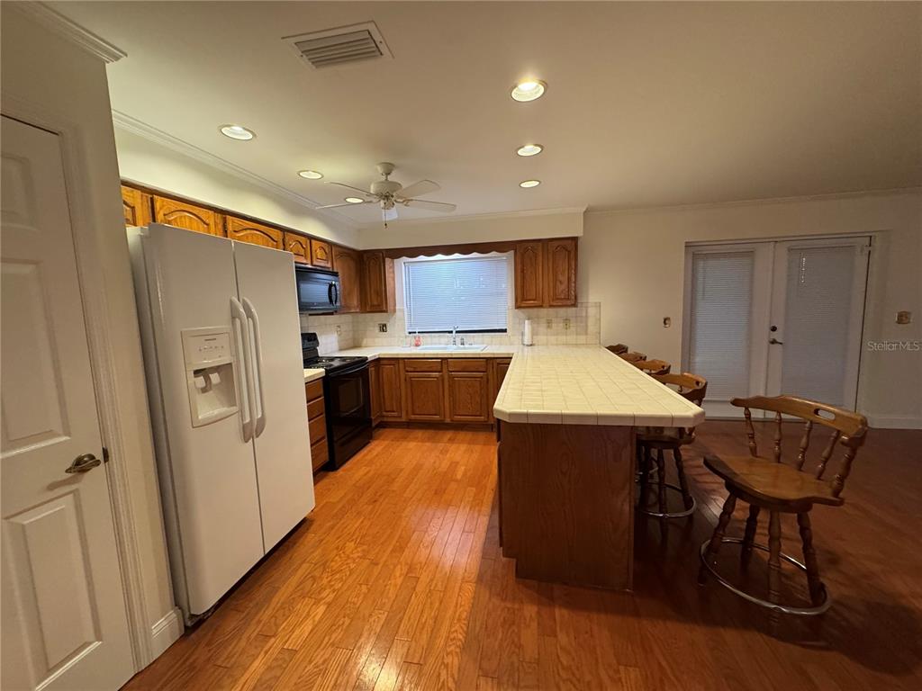 A kitchen features wood cabinets, a tiled island, black appliances, and hardwood flooring — 10 FT CLINCH HEIGHTS ROAD, FROSTPROOF, FL