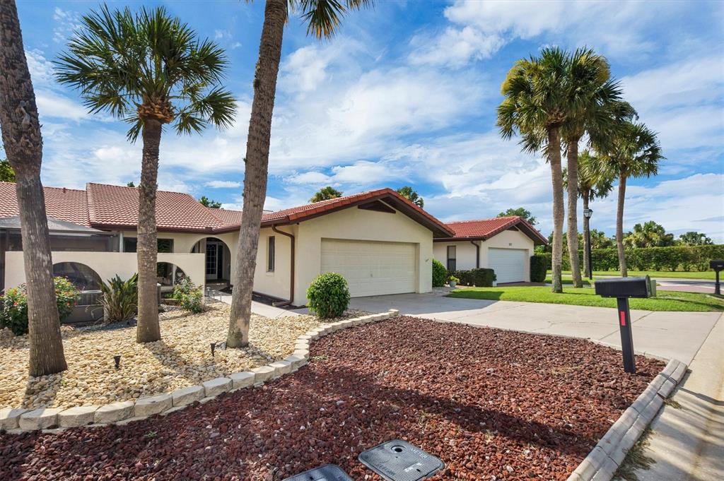 A beige house with a two-car garage and a concrete driveway under a blue sky — 503 CLUBHOUSE DRIVE, LAKE WALES, FL