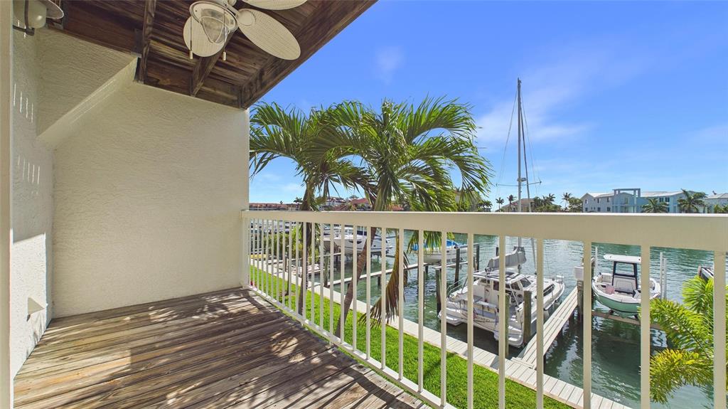A wooden balcony overlooks a canal with docked boats and palm trees — 323 MADEIRA CIRCLE, ST PETERSBURG, FL