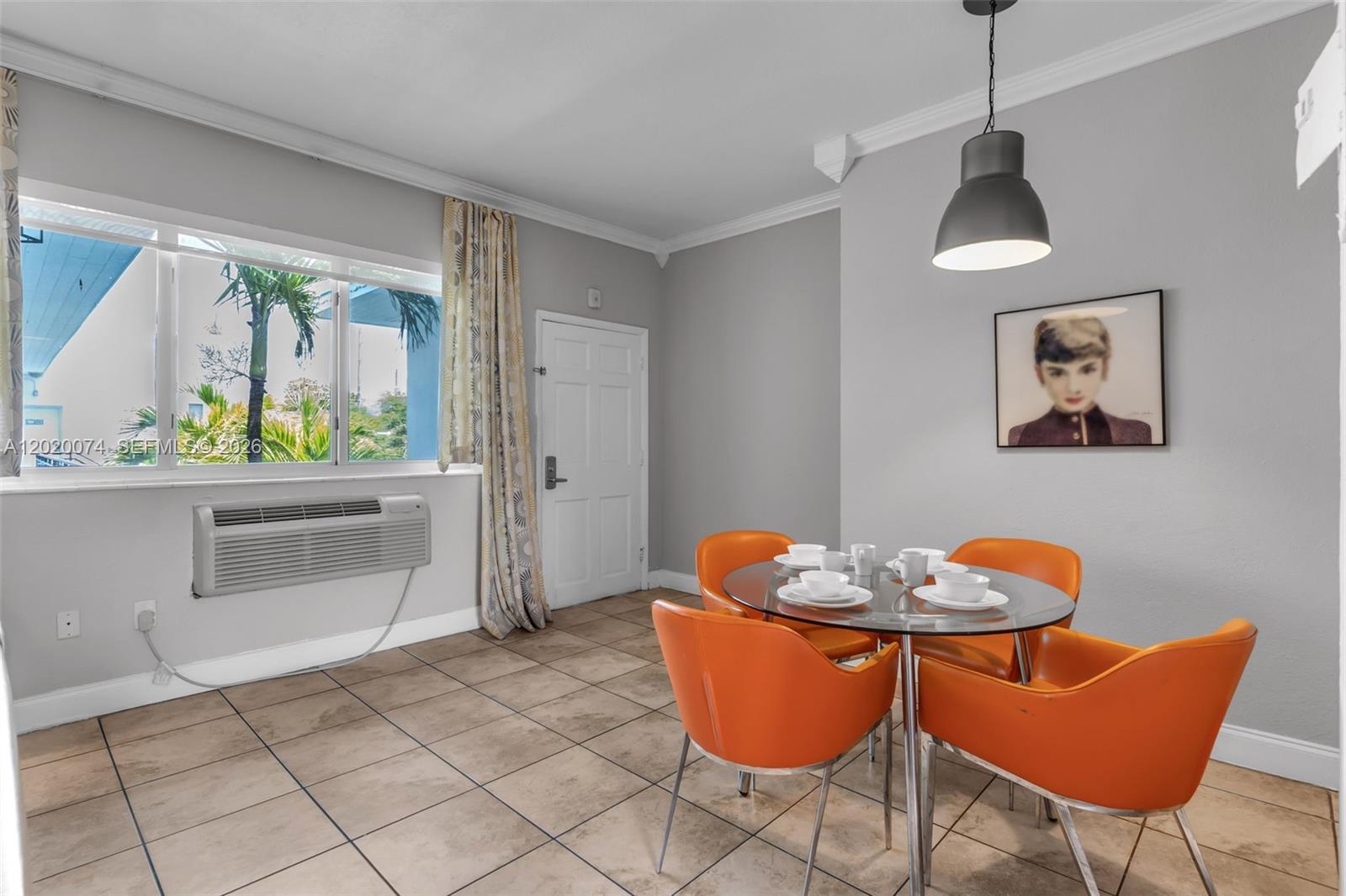 A dining area features a glass table with orange chairs, tile flooring, and a window — 8100 Harding Ave # 503, Miami Beach FL 33141, MIAMI BEACH, FL