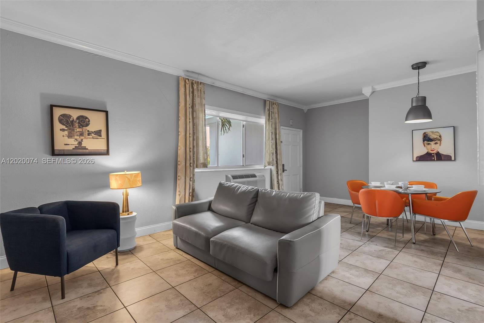 A living and dining room features gray walls, tile flooring, a gray sofa, and orange chairs — 8100 Harding Ave # 503, Miami Beach FL 33141, MIAMI BEACH, FL