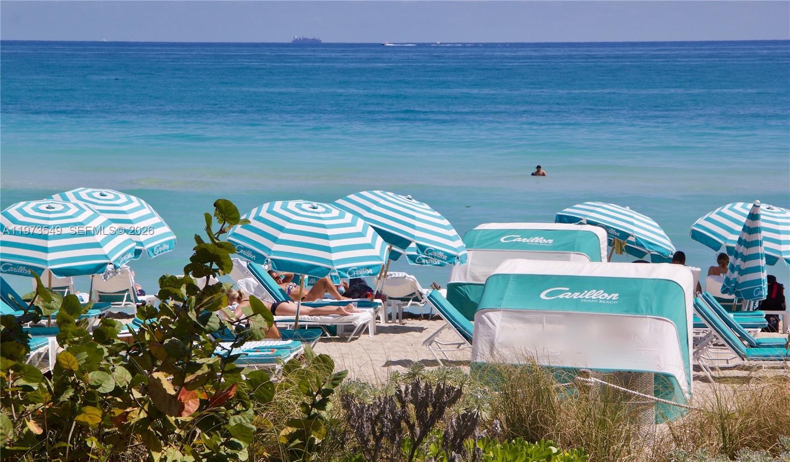 A beach scene features striped umbrellas and cabanas with lounge chairs on the sand — 6801 Collins Ave, Miami Beach FL 33141, MIAMI BEACH, FL