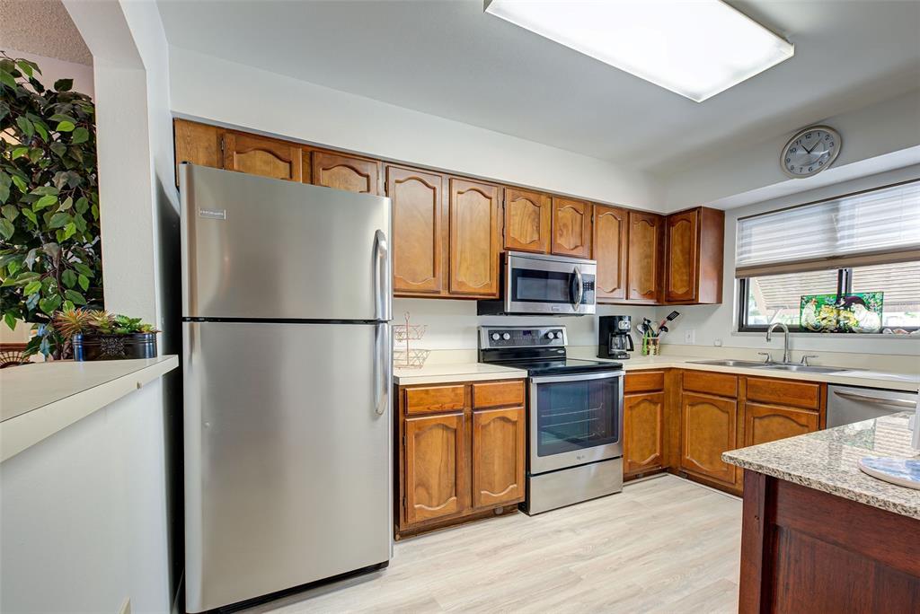A kitchen features wood cabinets, stainless steel appliances, and light-colored wood-look flooring — 5179 WILLOW LINKS UNIT 27, SARASOTA, FL