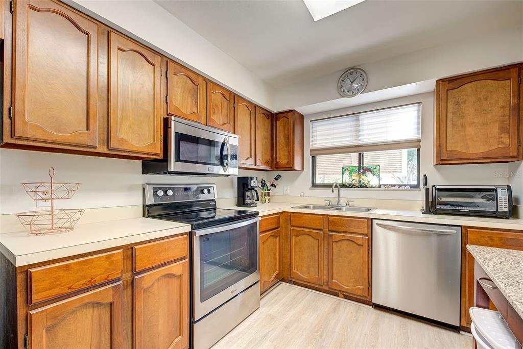 A kitchen with wood cabinets, stainless steel appliances, and a window above the sink — 5179 WILLOW LINKS UNIT 27, SARASOTA, FL