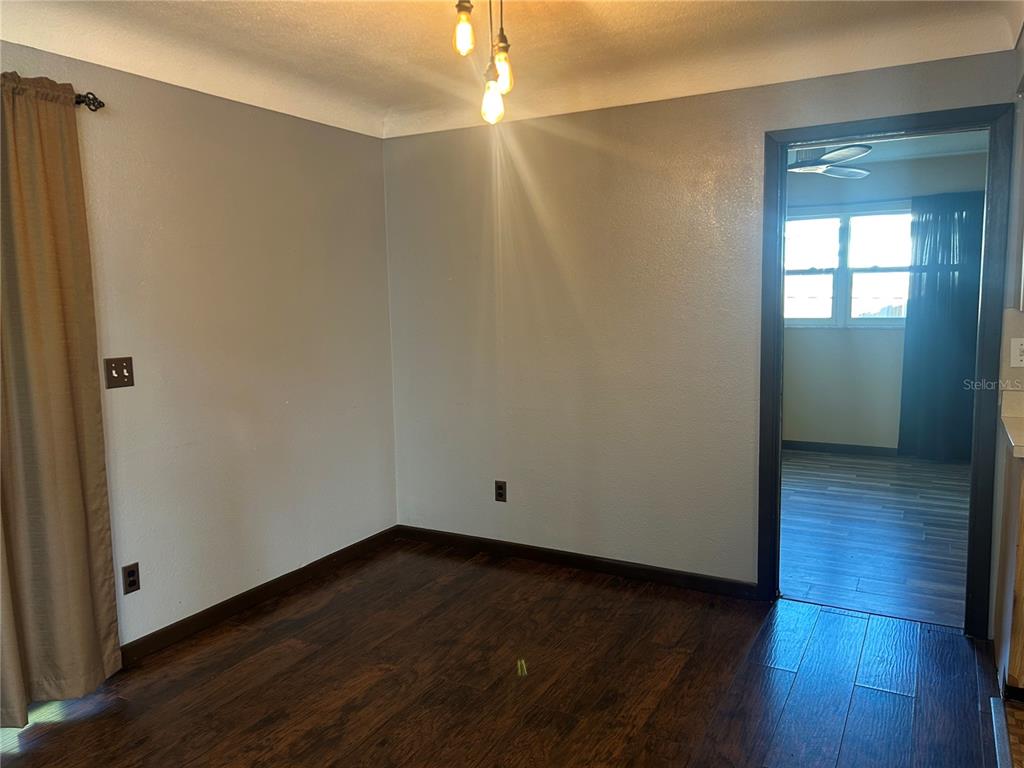 A dining room with gray walls, dark wood flooring, and a multi-bulb pendant light fixture — 13406 BELLEWOOD AVENUE, SEMINOLE, FL