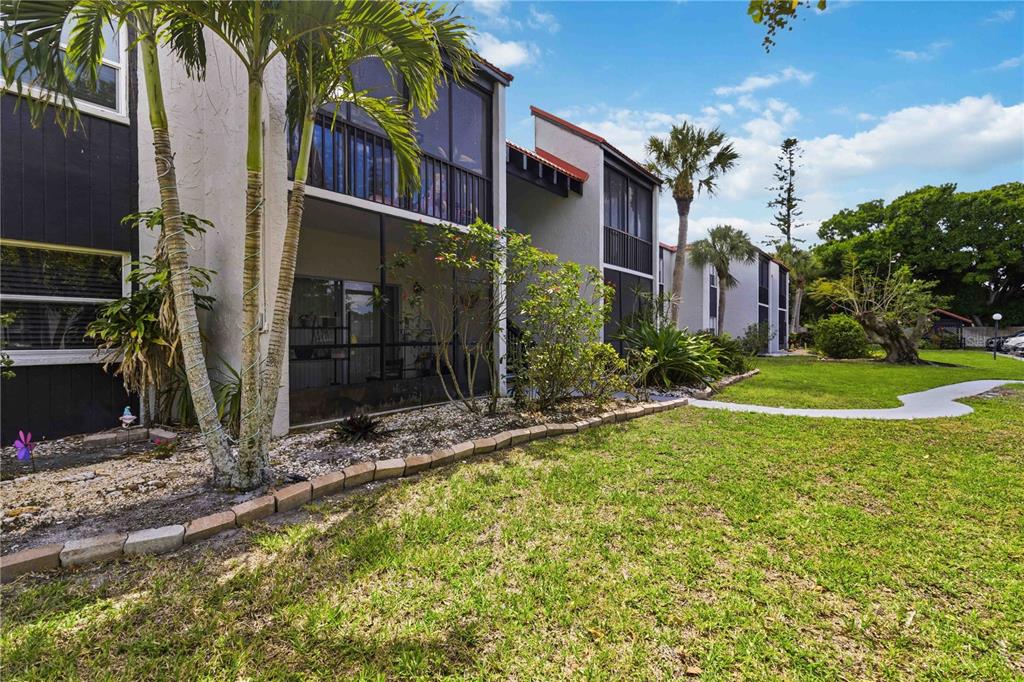 A multi-story apartment building with screened-in balconies, palm trees, and a grassy lawn — 3281 BENEVA ROAD UNIT 104, SARASOTA, FL