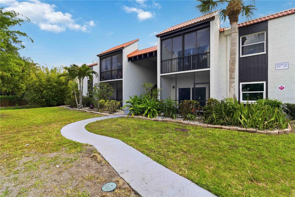 A two-story apartment building with screened balconies, a tiled roof, and a curved concrete walkway — 3281 BENEVA ROAD UNIT 104, SARASOTA, FL
