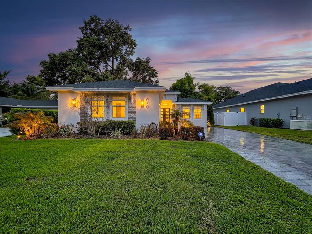 A single-story house with a white exterior, brick accents, and a paved driveway at dusk — 929 CLEARVIEW AVENUE, LAKELAND, FL