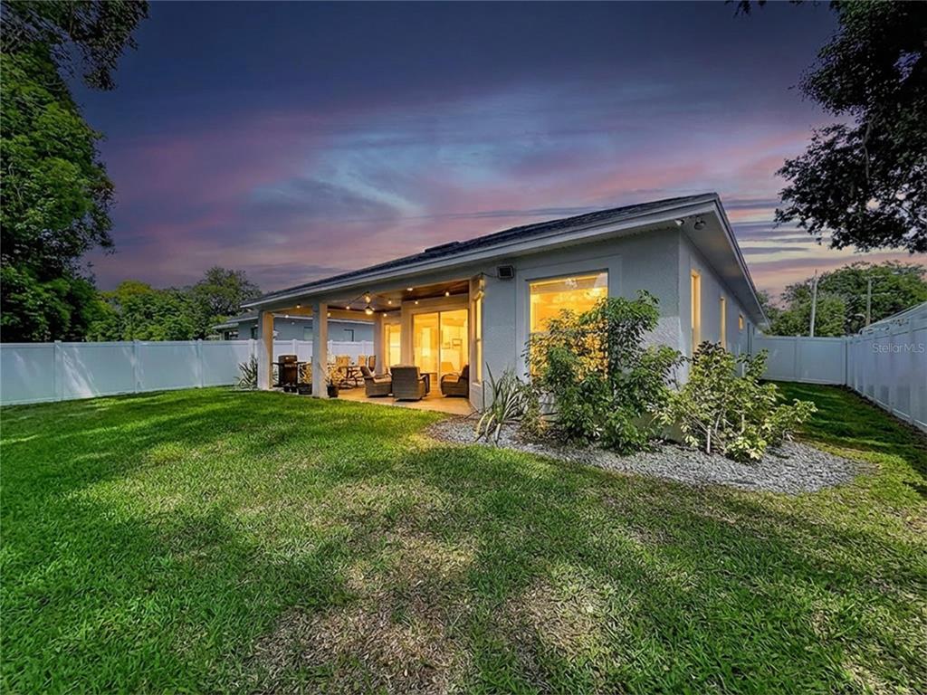 A backyard view of a house featuring a covered patio and a white vinyl fence — 929 CLEARVIEW AVENUE, LAKELAND, FL