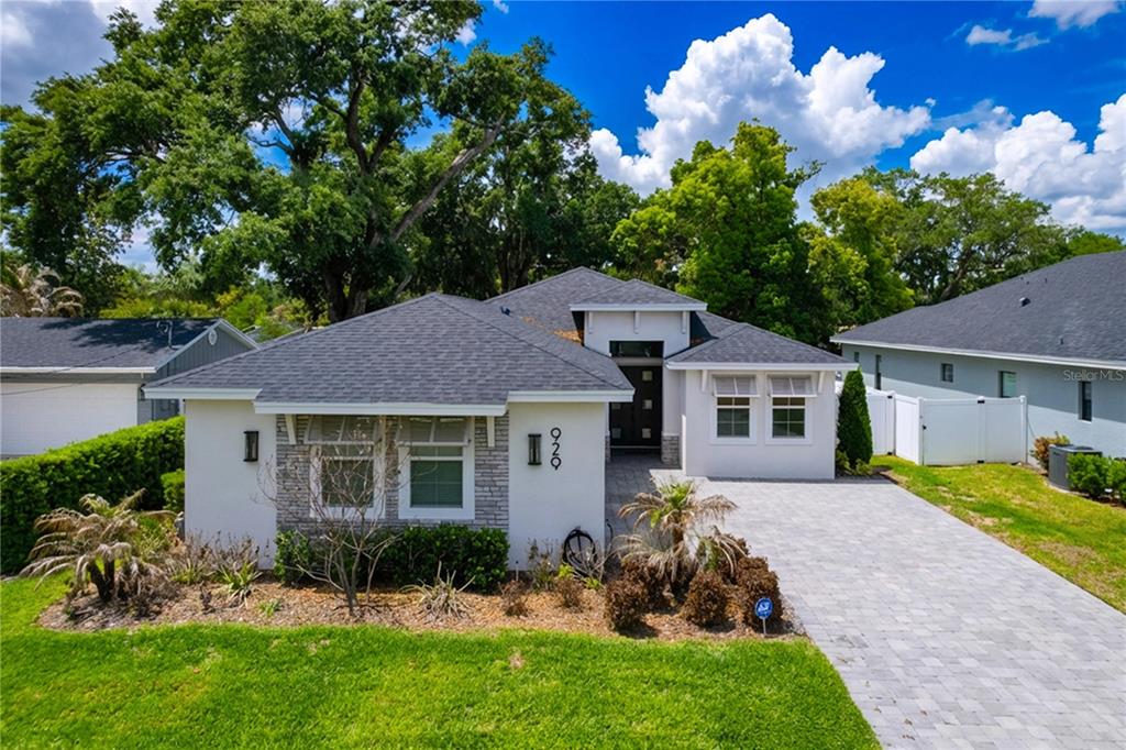 A single-story house with a gray shingled roof, white stucco walls, and stone accents — 929 CLEARVIEW AVENUE, LAKELAND, FL