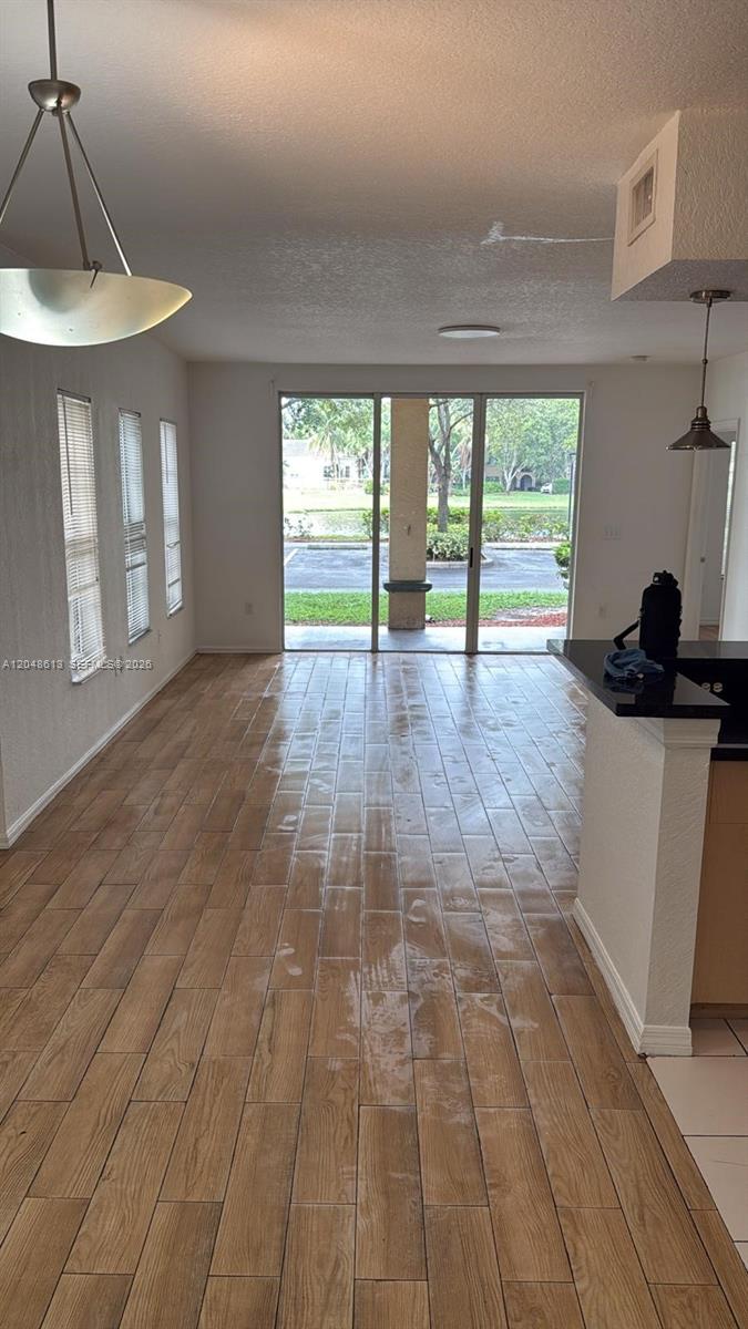 An open living area features wood-look tile flooring, a sliding glass door, and pendant lighting — 2541 Centergate Dr # 101, Miramar FL 33025, MIRAMAR, FL