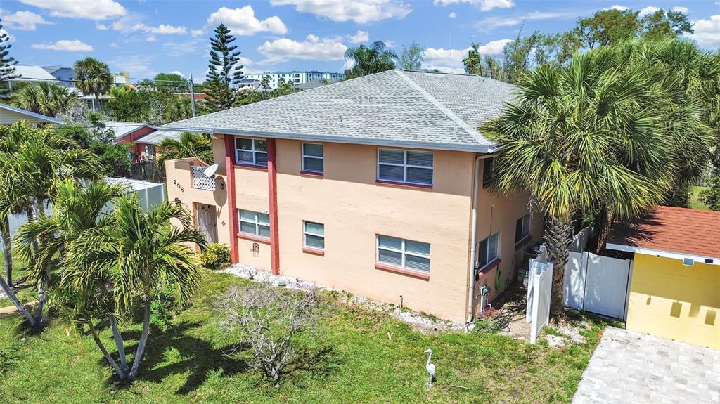 An exterior view of a two-story peach-colored apartment building with palm trees and landscaping — 206 22ND AVENUE, INDIAN ROCKS BEACH, FL