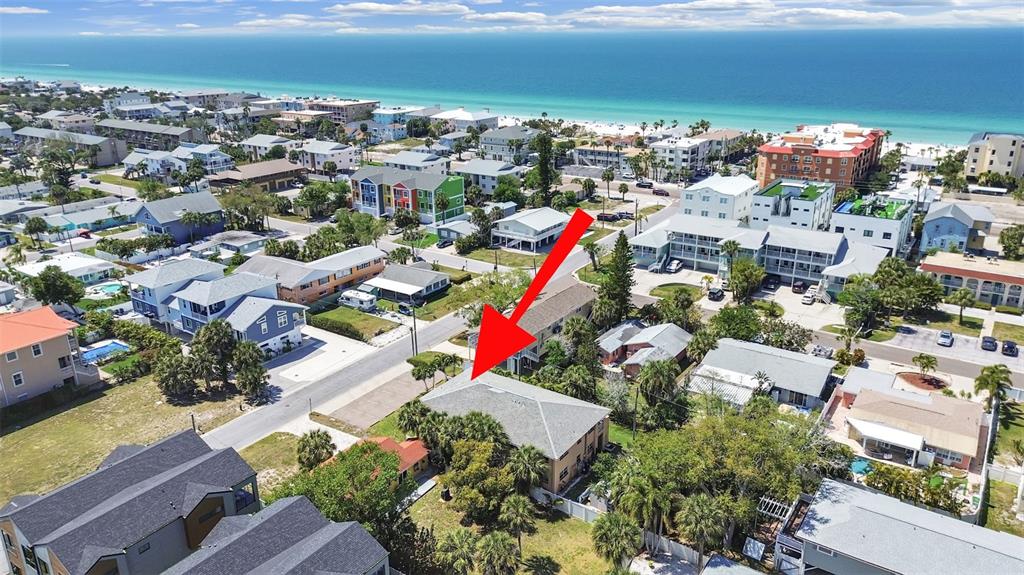 An aerial view shows a multi-story residential building surrounded by trees near the coast — 206 22ND AVENUE, INDIAN ROCKS BEACH, FL