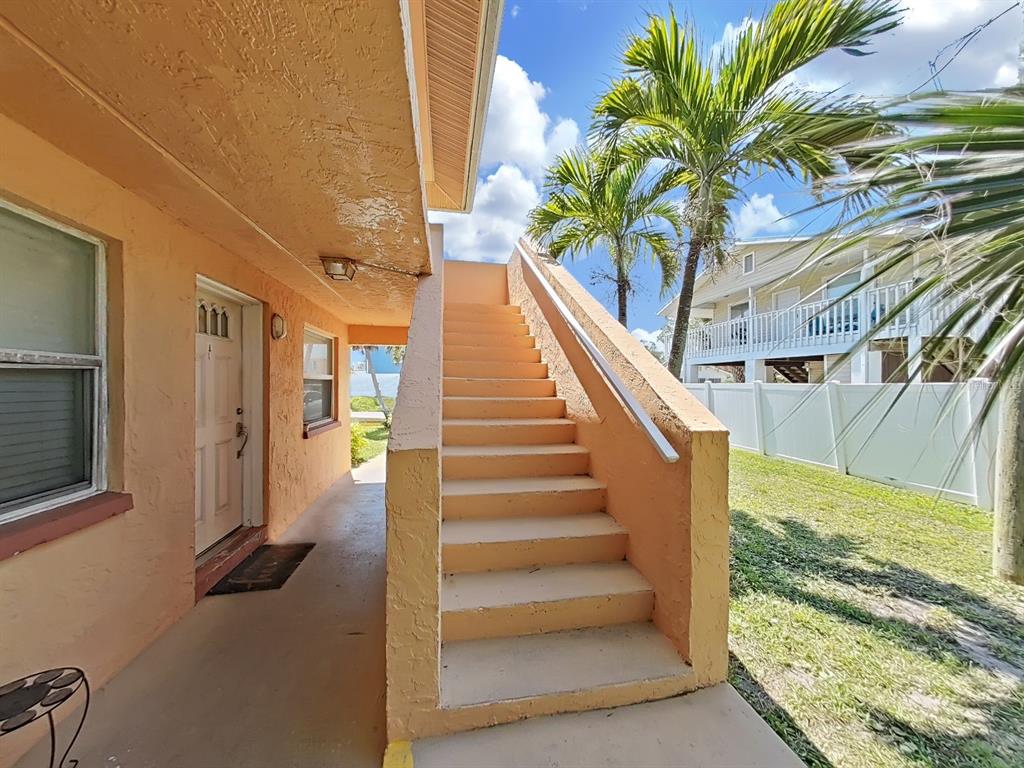 An exterior view of a peach-colored building with a concrete staircase leading to an upper level — 206 22ND AVENUE, INDIAN ROCKS BEACH, FL