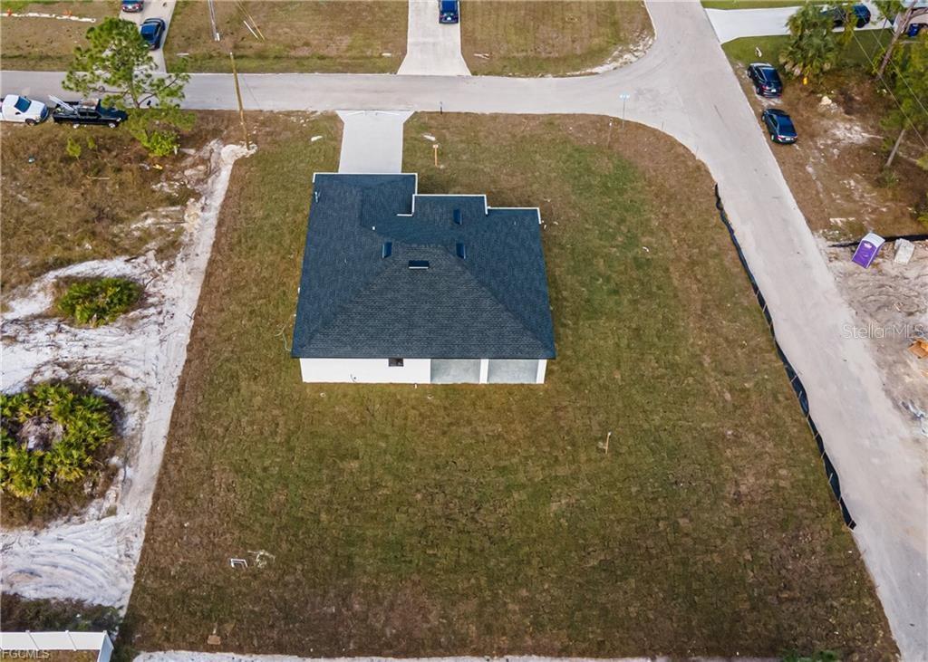 An aerial view shows a newly constructed house on a corner lot with grass — 3701 28TH STREET SW, LEHIGH ACRES, FL