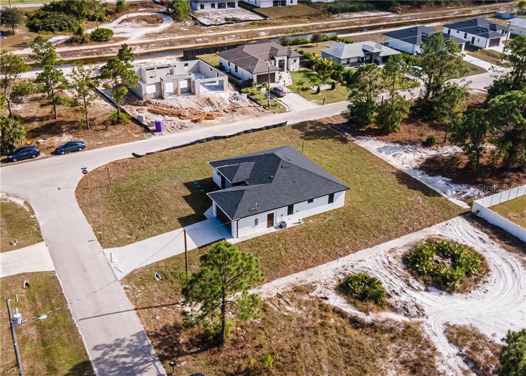 An aerial view shows a single-story house with a dark roof on a grassy lot — 3701 28TH STREET SW, LEHIGH ACRES, FL