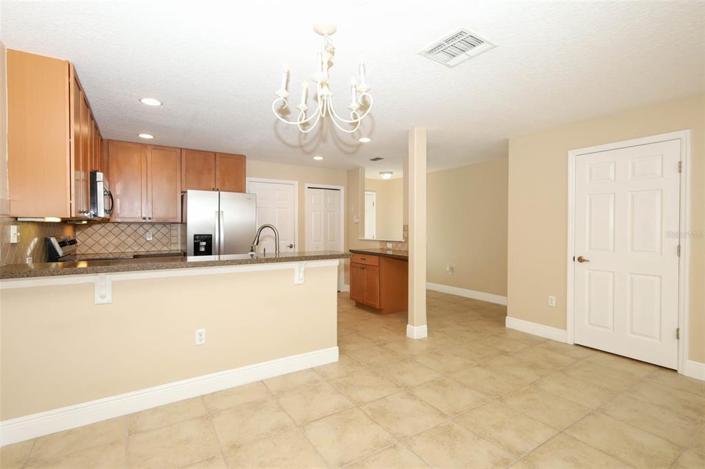 A kitchen with wood cabinets, stainless steel appliances, and a breakfast bar overlooks a dining area — 162 CONSTITUTION WAY, WINTER SPRINGS, FL