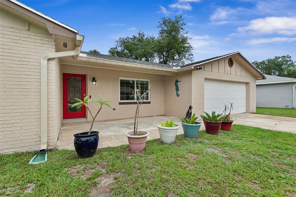 A single-story brick house features a red front door, a garage, and several potted plants — 3 OVERBROOK COURT, ORMOND BEACH, FL