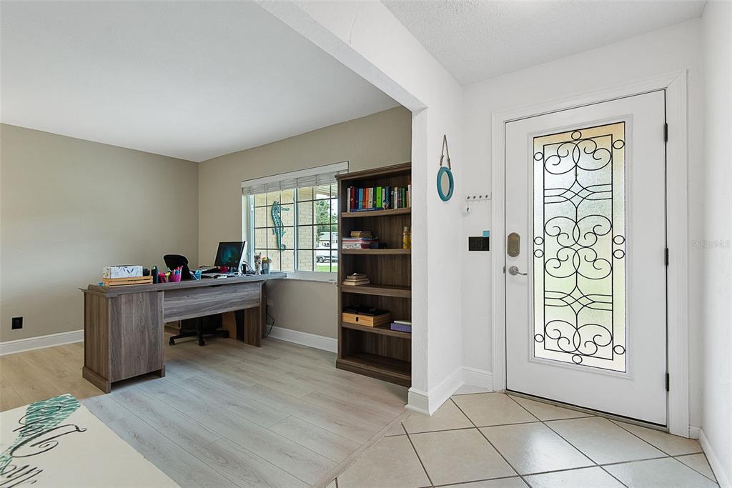 A home office with a desk and bookshelf sits next to an entryway with tile — 3 OVERBROOK COURT, ORMOND BEACH, FL