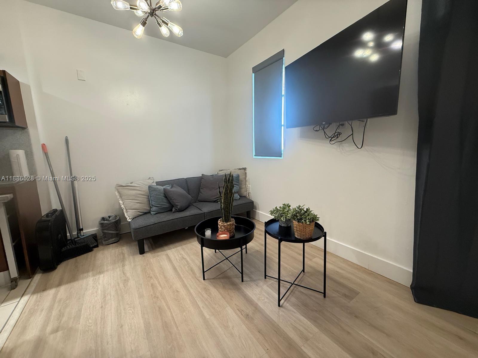 A small living area features a gray sofa, two round coffee tables, and a wall-mounted television — 1036 Ocean Dr # B303, Miami Beach FL 33139, MIAMI BEACH, FL