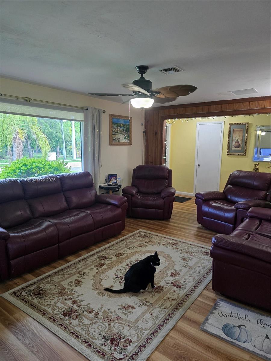 A living room features a black cat on a rug, purple leather furniture, and wood-paneled walls — 19500 SW 87th Ave, Cutler Bay FL 33157, CUTLER BAY, FL
