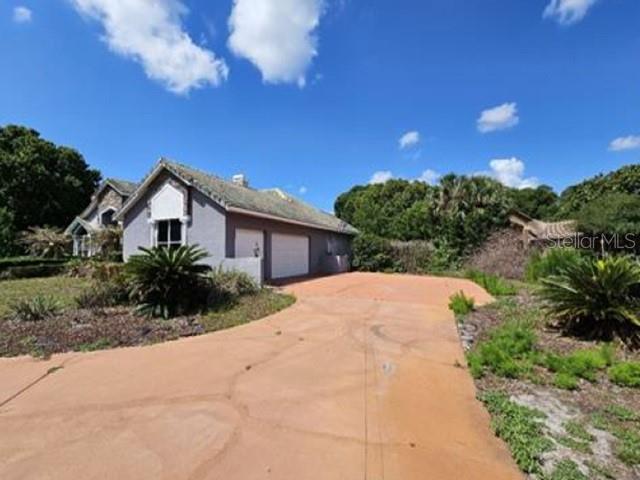 A single-story house with a two-car garage and a large concrete driveway under a blue sky — 2128 LAKE CRESCENT COURT, WINDERMERE, FL