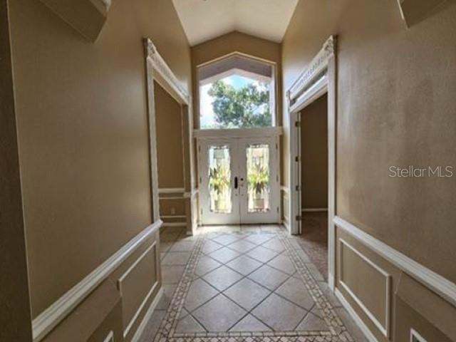 An entryway with tile flooring, beige walls, white wainscoting, and double front doors — 2128 LAKE CRESCENT COURT, WINDERMERE, FL