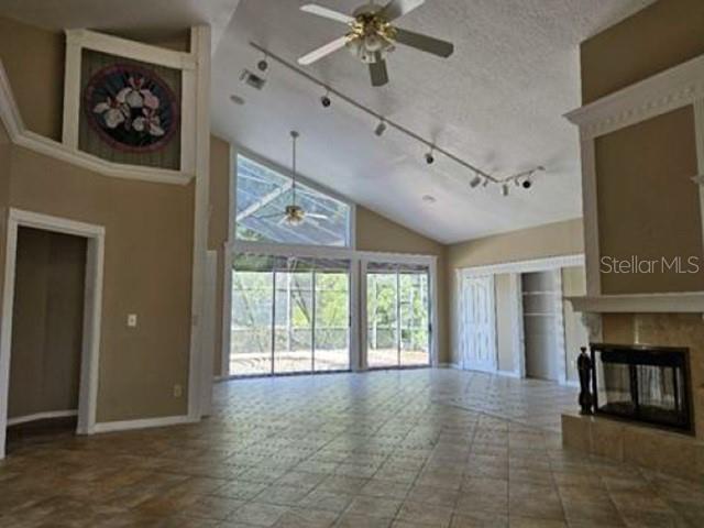 A spacious living room features tile floors, a vaulted ceiling, a fireplace, and large windows — 2128 LAKE CRESCENT COURT, WINDERMERE, FL