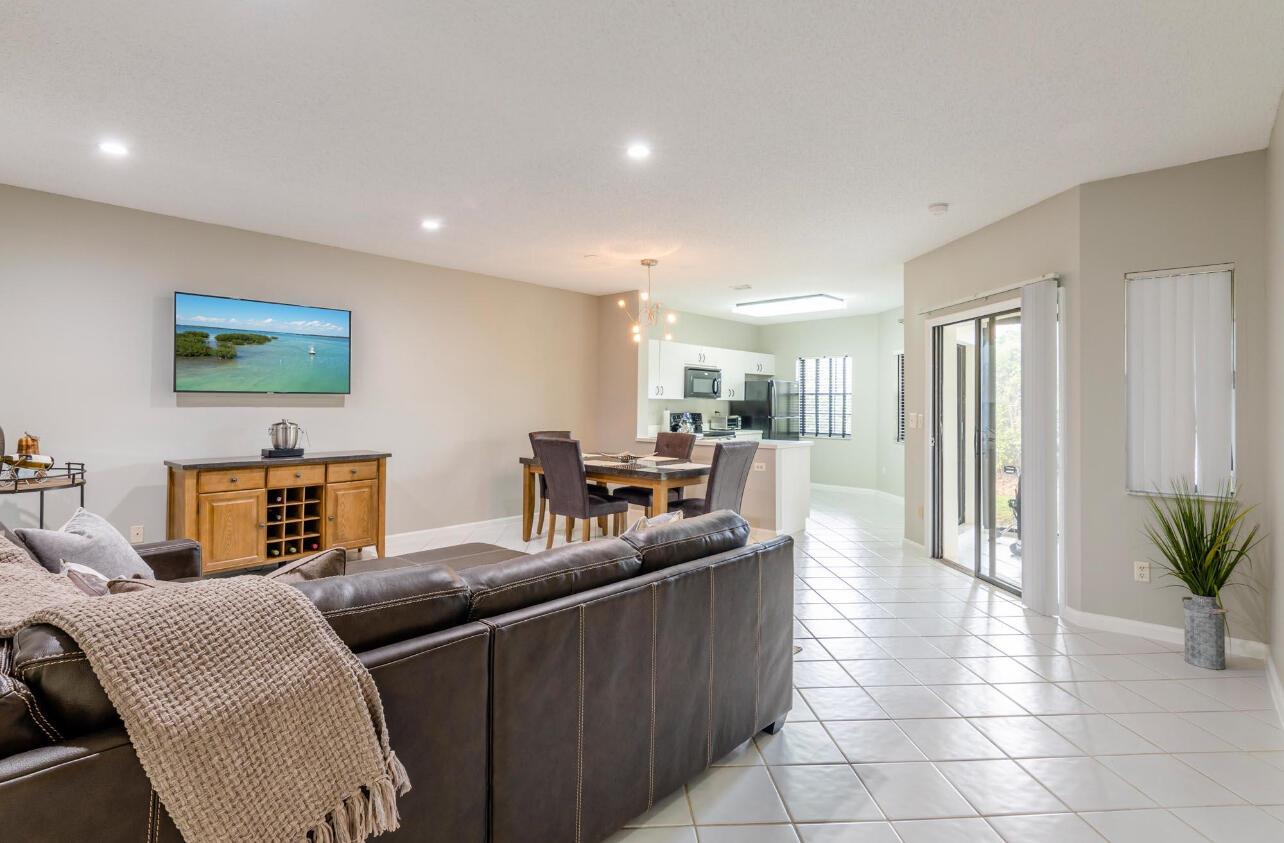 An open-concept living and dining area with tile floors, a leather sofa, and sliding doors — 6666 Montego Bay Boulevard, Boca Raton FL 33433, BOCA RATON, FL