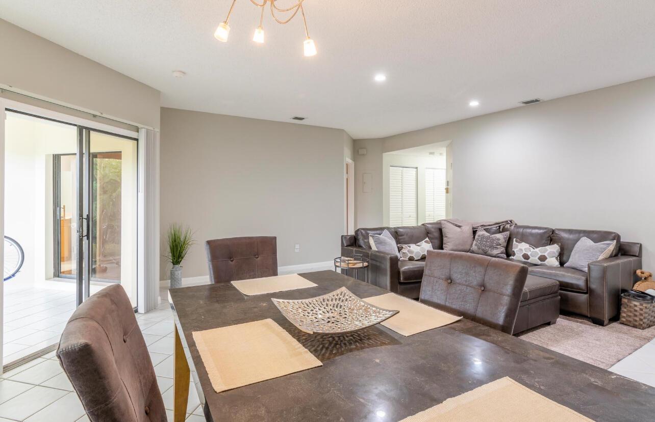 A dining area with a dark table and chairs opens to a living room with sofa — 6666 Montego Bay Boulevard, Boca Raton FL 33433, BOCA RATON, FL