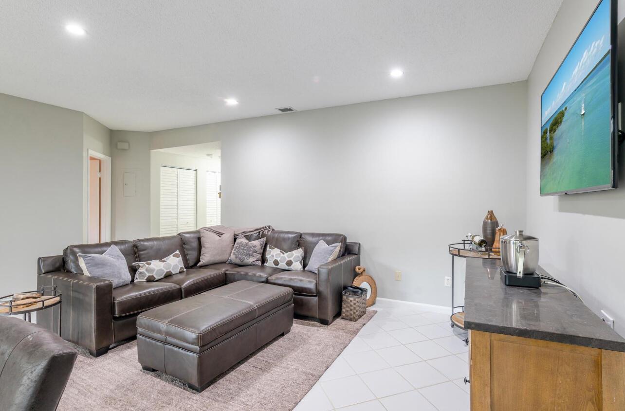 A living room features a brown leather sectional, a matching ottoman, and a wall-mounted television — 6666 Montego Bay Boulevard, Boca Raton FL 33433, BOCA RATON, FL