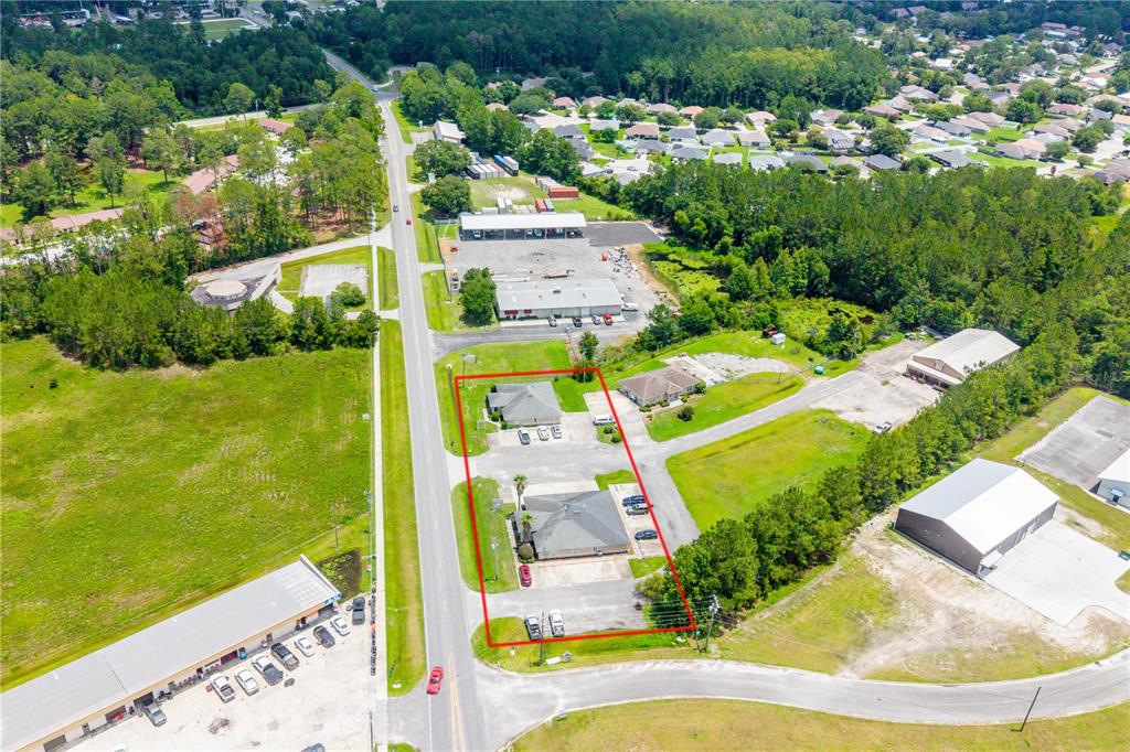 An aerial view shows two commercial buildings on a lot outlined in red near a road — 853 SW SISTERS WELCOME ROAD, LAKE CITY, FL