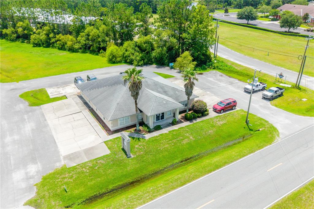 An aerial view shows a single-story commercial building with a gray roof and two palm trees — 853 SW SISTERS WELCOME ROAD, LAKE CITY, FL