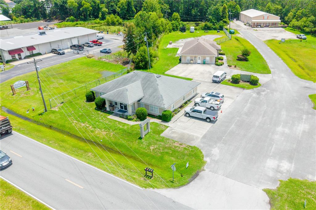 An aerial view shows a commercial property with two buildings, parking lots, and grassy areas — 853 SW SISTERS WELCOME ROAD, LAKE CITY, FL