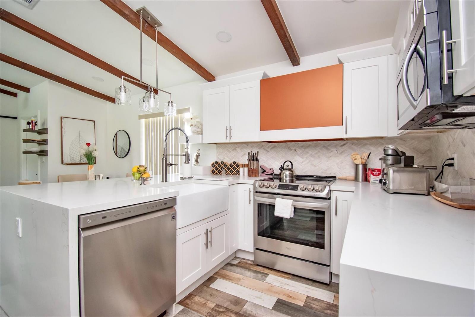 A kitchen with white cabinets, a copper-colored range hood, stainless steel appliances, and wood beams — 6557 Country Wood Way, Delray Beach FL 33484, DELRAY BEACH, FL