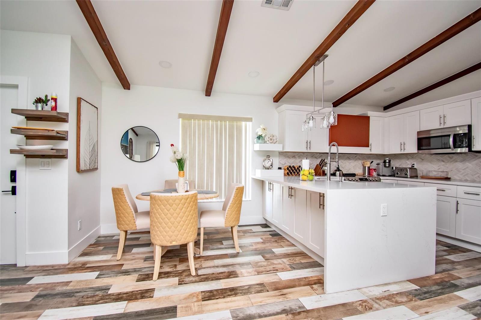 A kitchen and dining area with white cabinets, a quartz island, and wood-look tile flooring — 6557 Country Wood Way, Delray Beach FL 33484, DELRAY BEACH, FL