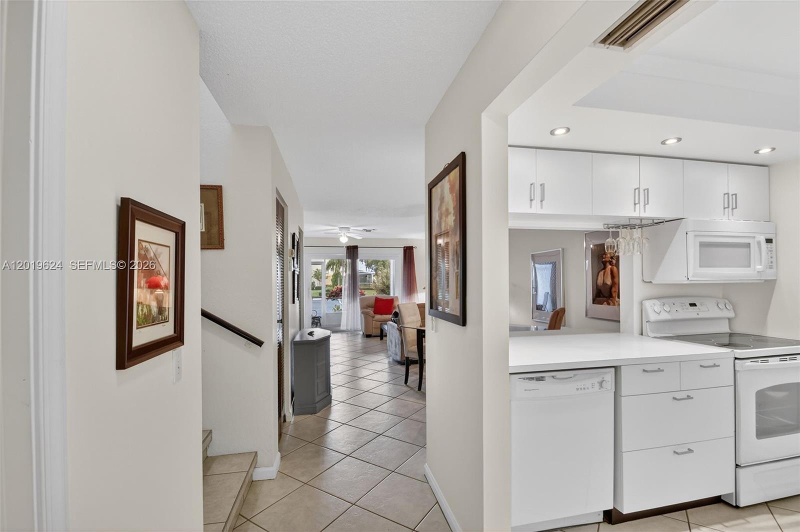 A tiled hallway leads from a white kitchen toward a living area with sliding doors — 341 Waterside Dr # 341, Hypoluxo FL 33462, HYPOLUXO, FL