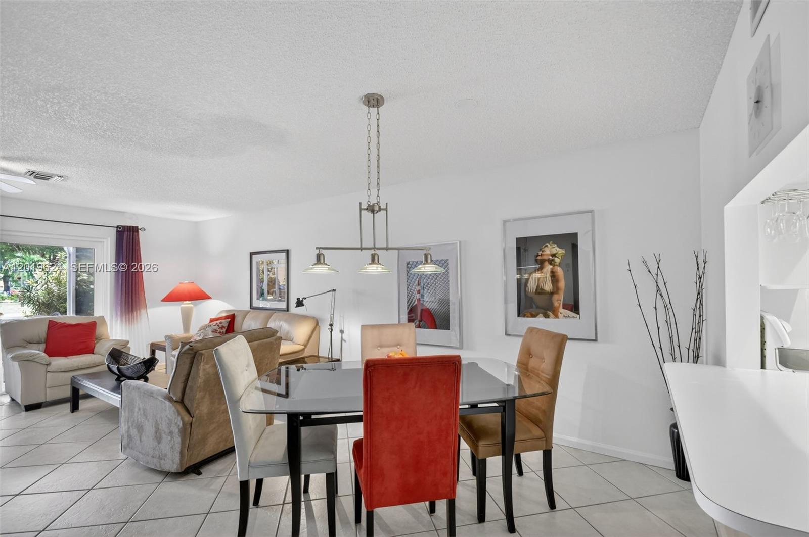 A dining area with a glass table and chairs sits adjacent to a living room — 341 Waterside Dr # 341, Hypoluxo FL 33462, HYPOLUXO, FL