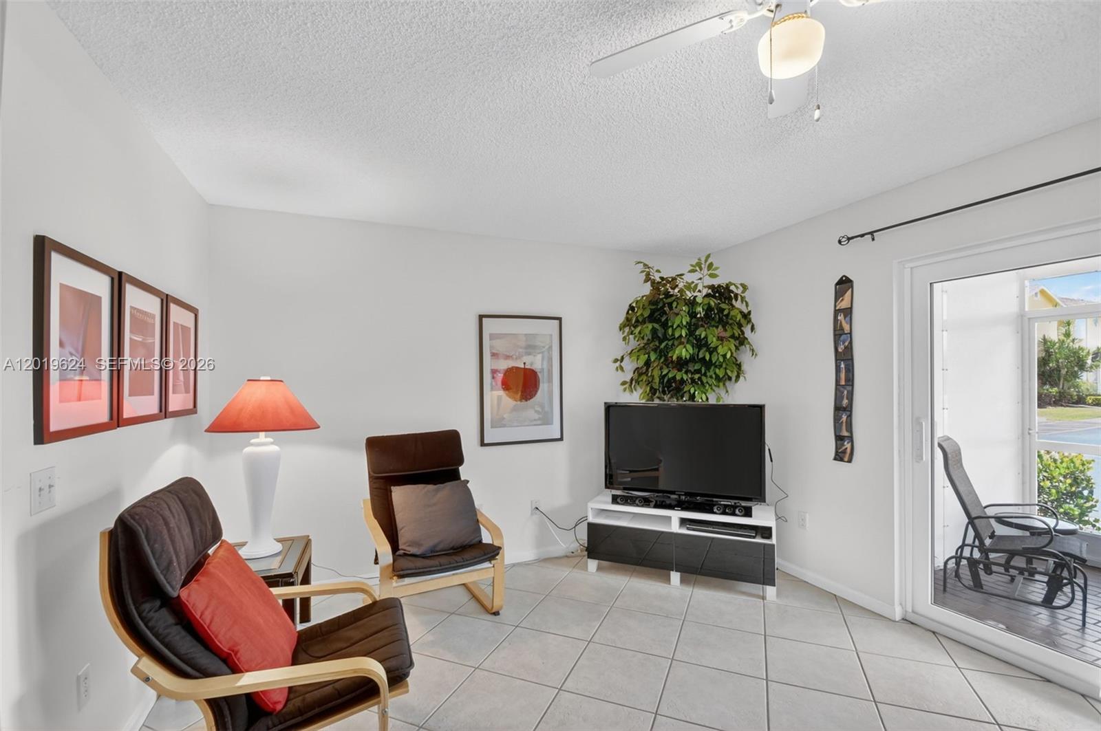 A living room features tile floors, two armchairs, a television on a stand, and a patio — 341 Waterside Dr # 341, Hypoluxo FL 33462, HYPOLUXO, FL