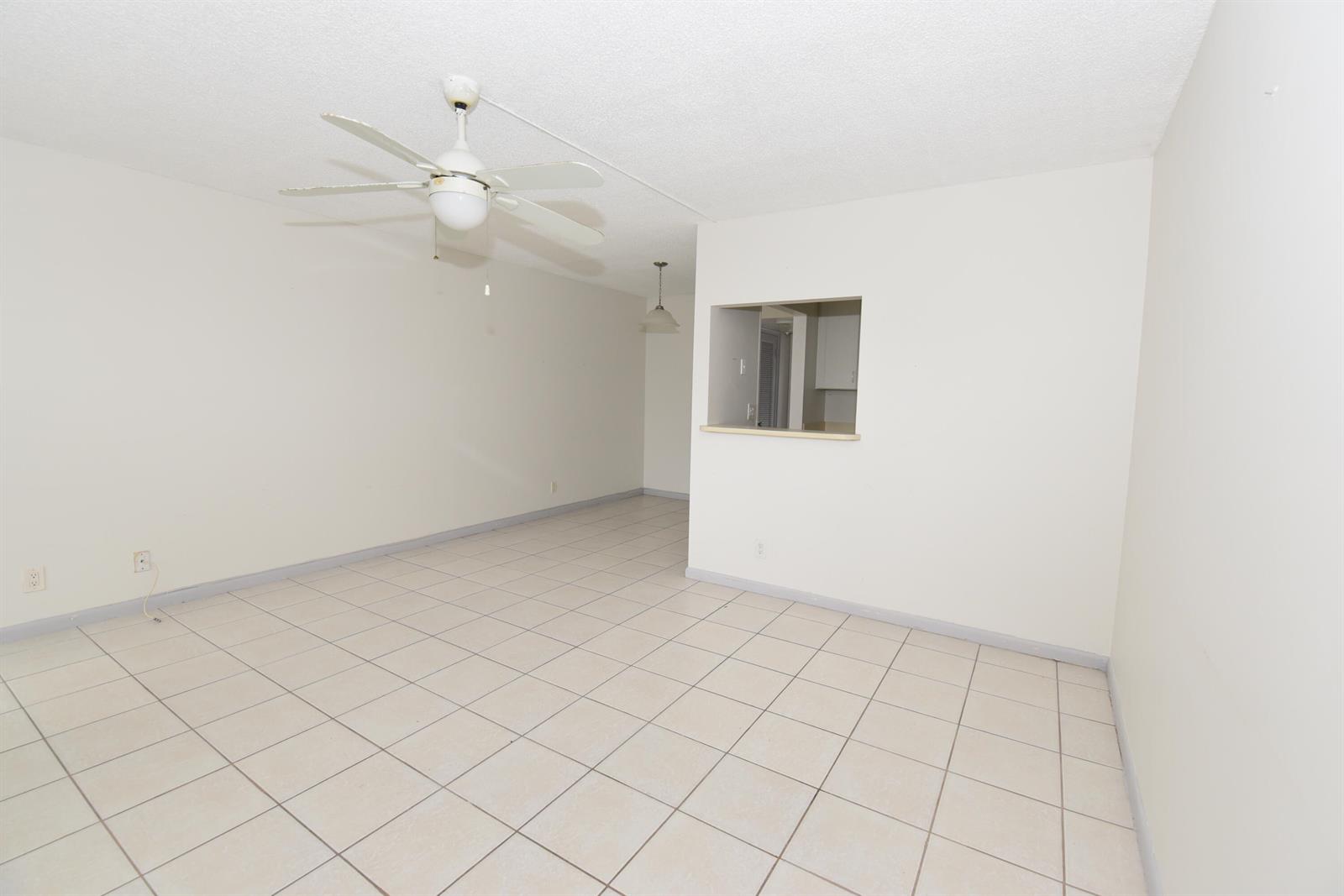 An empty living room features white walls, light-colored floor tiles, and a ceiling fan — 164 Andover G, West Palm Beach FL 33417, WEST PALM BEACH, FL