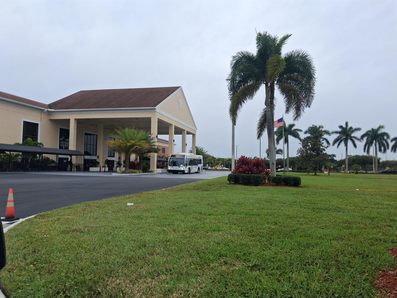 A white bus pulls up to the entrance of a large building with palm trees — 105 Suffolk C # 105, Boca Raton FL 33434, BOCA RATON, FL