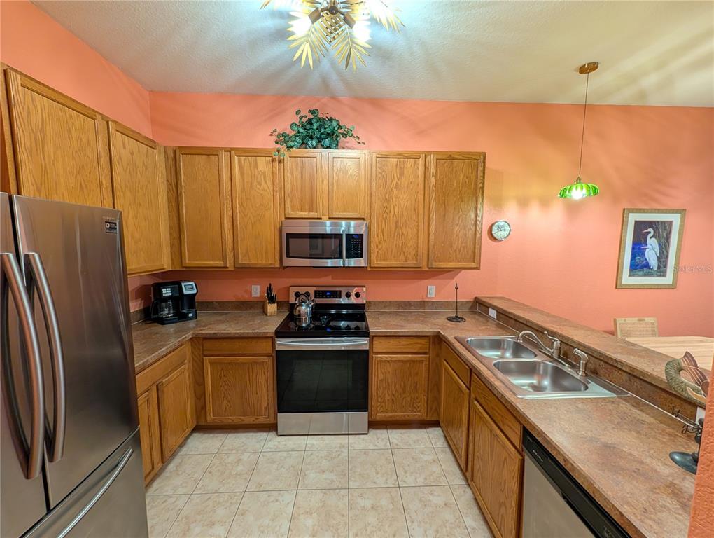 A kitchen with oak cabinets, stainless steel appliances, and peach-colored walls — 210 WATLING WAY UNIT 24-210, DAVENPORT, FL