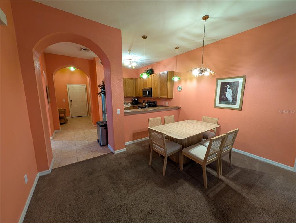 A dining area with a table and chairs sits adjacent to an open kitchen — 210 WATLING WAY UNIT 24-210, DAVENPORT, FL