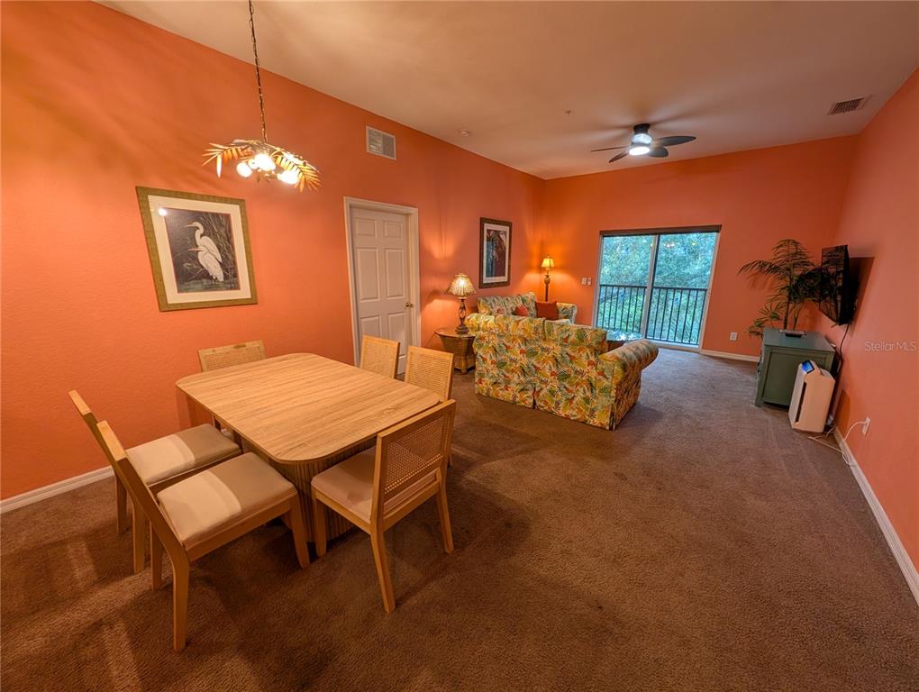 A dining area with a table and chairs opens into a living room with carpet — 210 WATLING WAY UNIT 24-210, DAVENPORT, FL