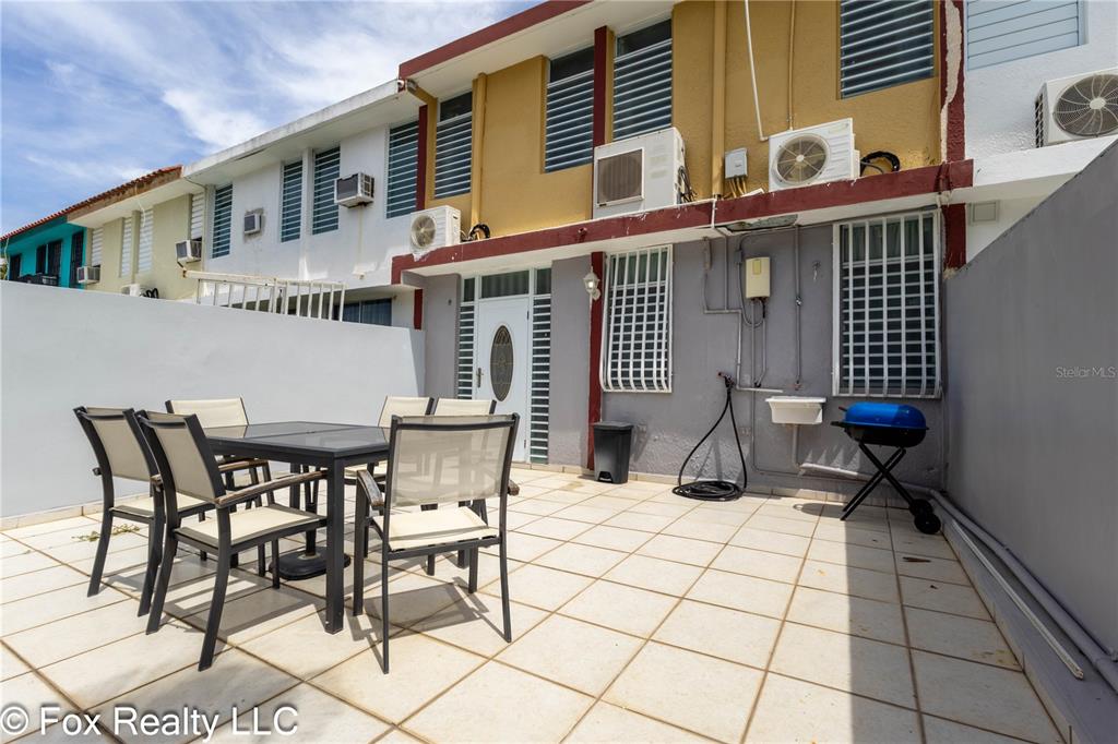 A paved outdoor patio features a dining set, a grill, and a white exterior wall — B4 URB VISTA AZUL, RINCON, PR
