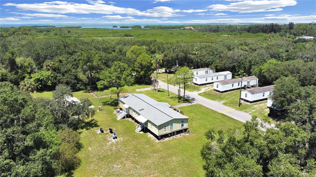 An aerial view shows several mobile homes situated on a grassy lot surrounded by trees — 6304 EUGENE ACRES LANE, GIBSONTON, FL