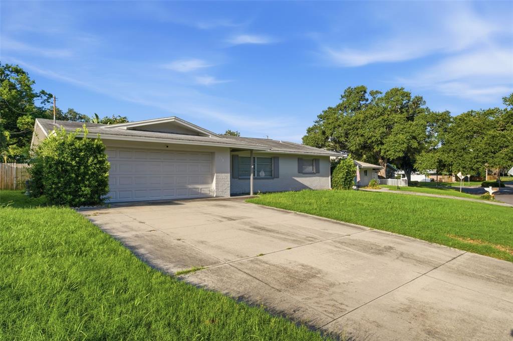 A single-story house with a concrete driveway, a two-car garage, and a large front lawn — 1387 BELLEVUE BOULEVARD, CLEARWATER, FL
