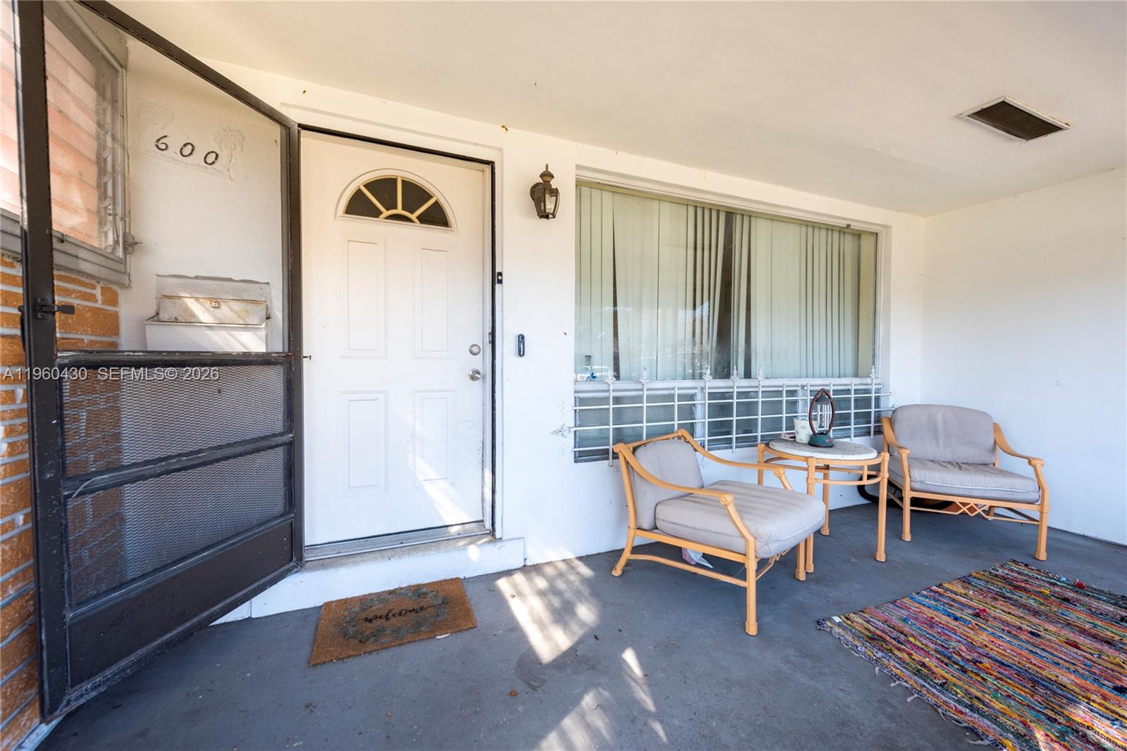 A covered front porch features a white door, a large window, and two patio chairs — 600 SW 11th Ave, Hallandale Beach FL 33009, HALLANDALE BEACH, FL