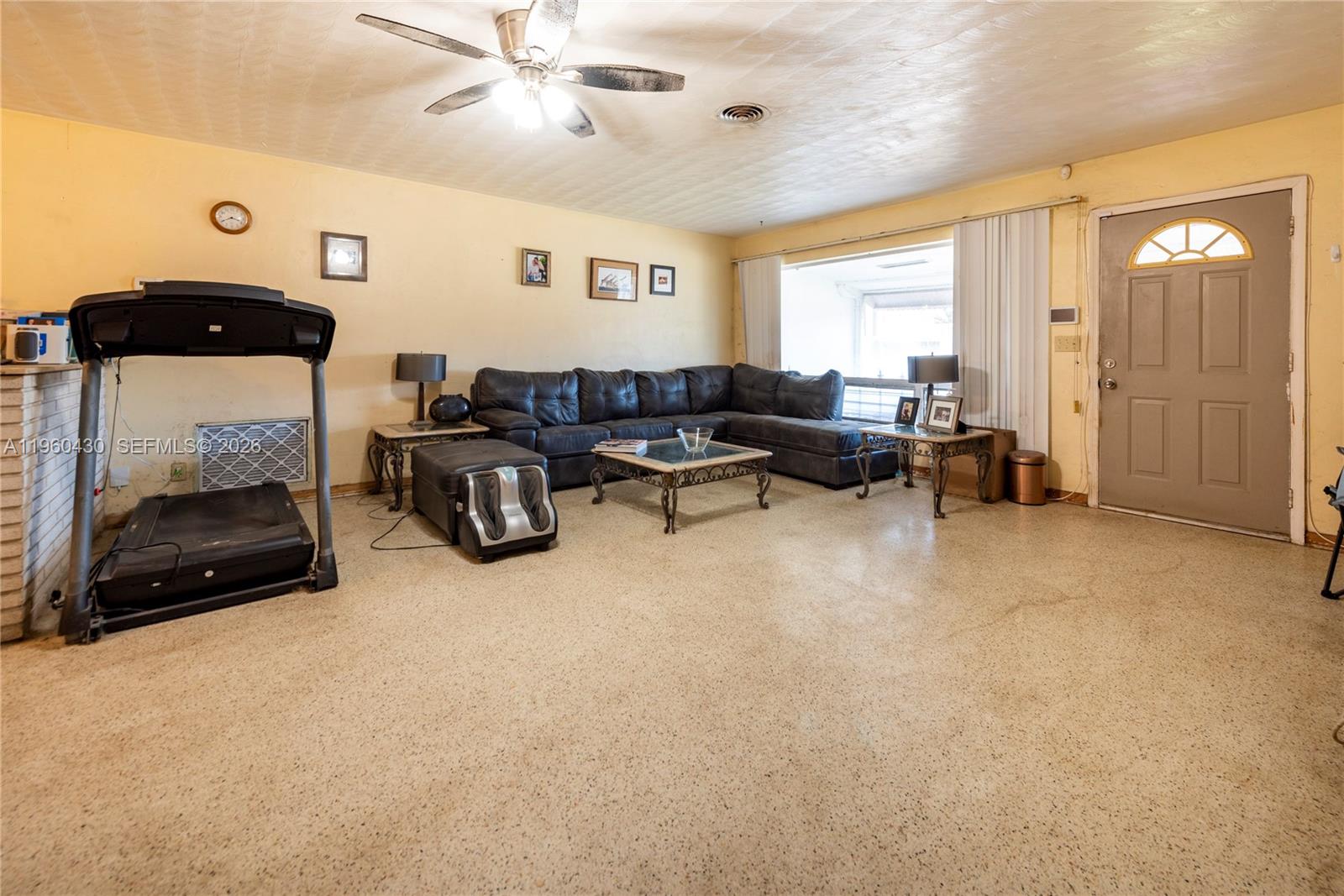 A living room features a treadmill, a sectional sofa, and a front door — 600 SW 11th Ave, Hallandale Beach FL 33009, HALLANDALE BEACH, FL